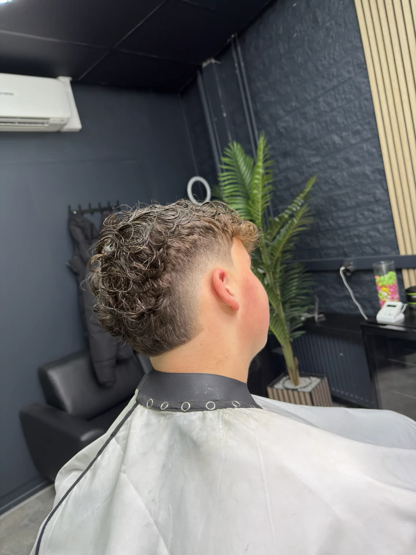 Professionele barbershop haircut met lage skin fade en scherpe hairline.